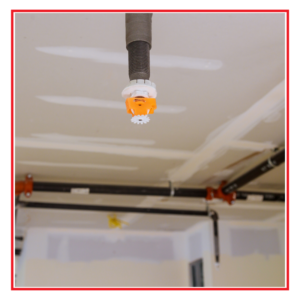 An image of a fire sprinkler, including an open ceiling and building materials.