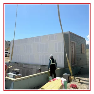 Image of a modular house under construction. Shows shell being hoisted into place. 