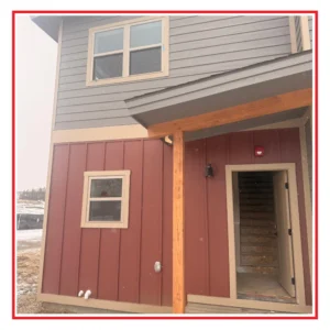 Partially completed modular house. Two-story rust and gray with a front porch.
