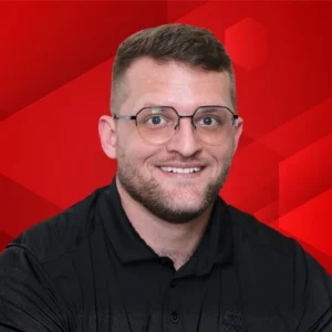 James Trimble is a male with dark hair and glasses. He is wearing a black shirt 