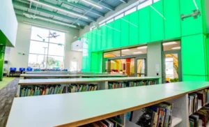 Interior shot showing a vibrant wall of green with library book shelves filled with books. Airplanes hang from the ceiling.